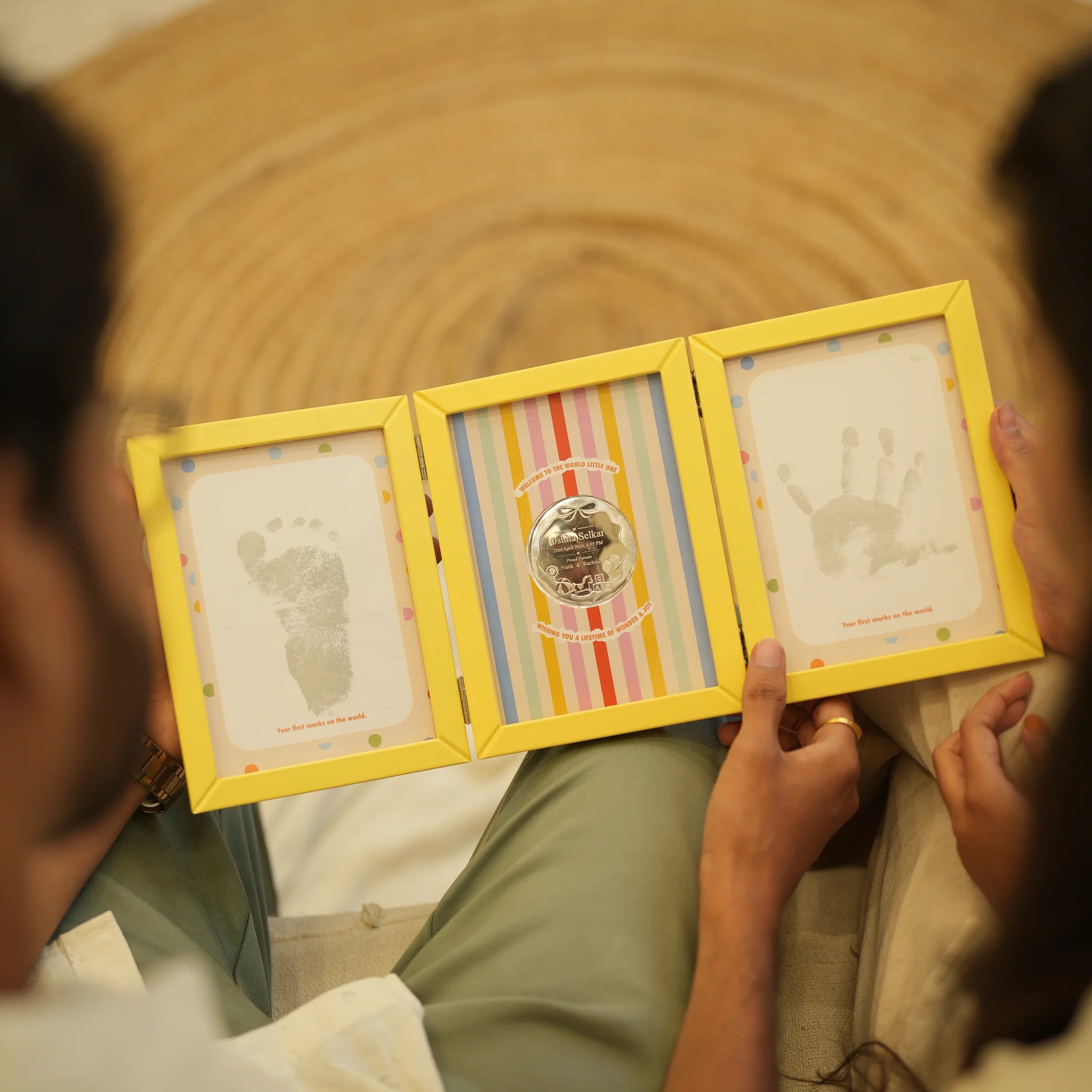 Parents holding the First Impressions Three Fold frame with baby footprint, personalised silver coin and handprint by Adorn Silver