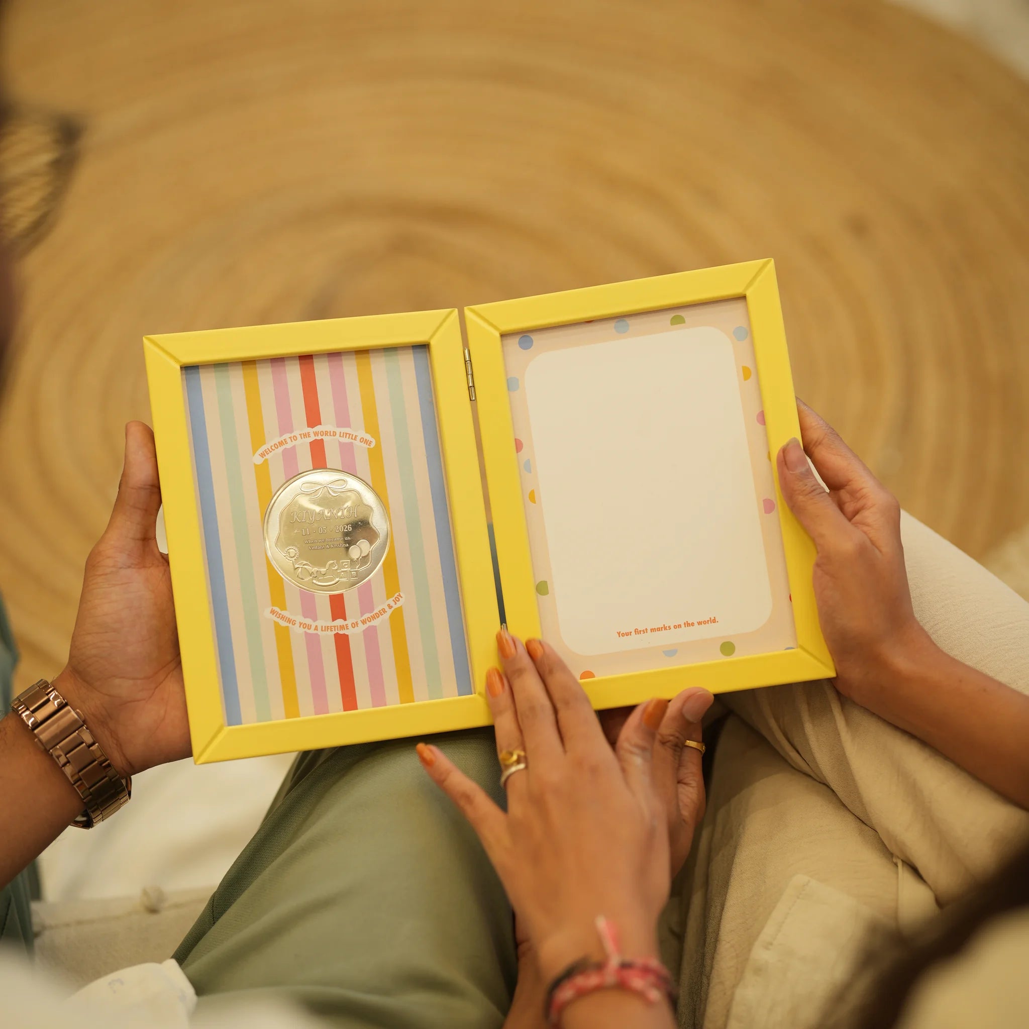 Parents holding the First Impressions Two Fold frame with a personalised silver baby coin by Adorn Silver