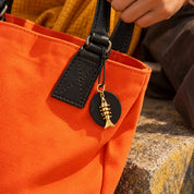 Gold finish fish charm clipped to a tote bag