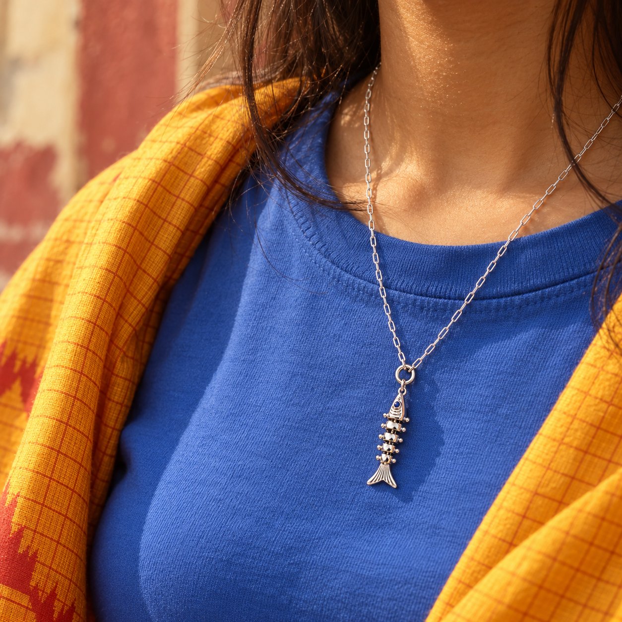 Silver fish charm worn on a chain necklace