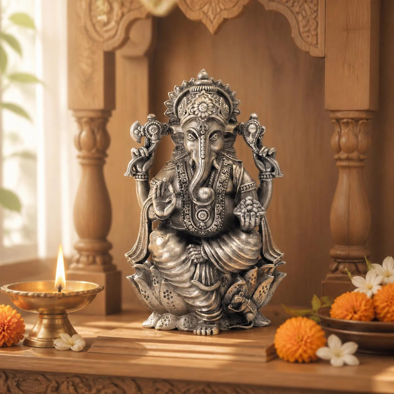 Silver left-trunk Lord Ganesh idol on a lotus in a home mandir with brass diya and marigolds