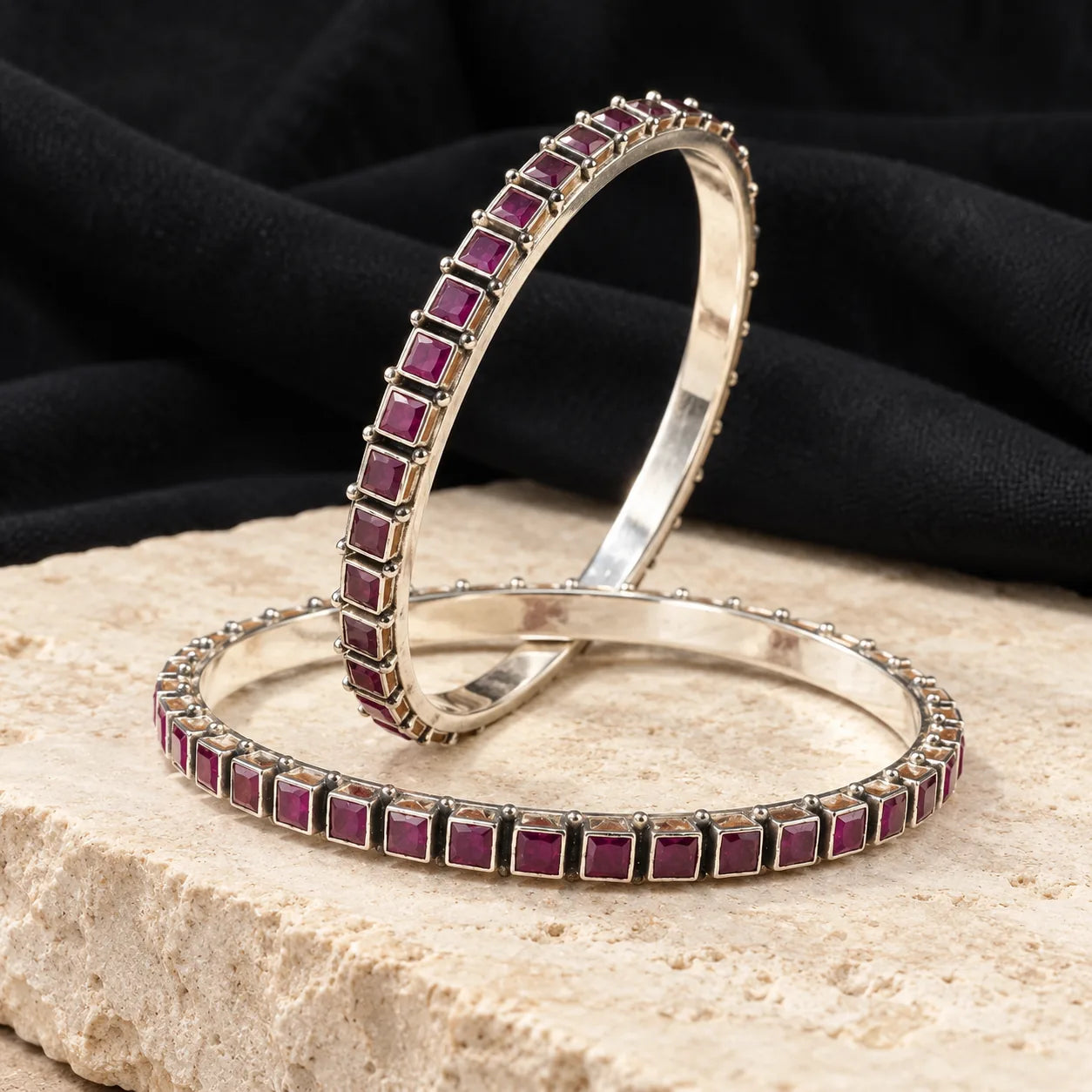 Square-set red stone silver bangles, styled