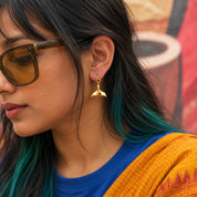 Gold finish whale tail charm worn as an earring