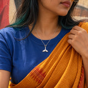 Whale tail silver charm worn on a chain necklace