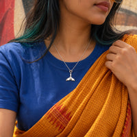 Whale tail silver charm worn on a chain necklace